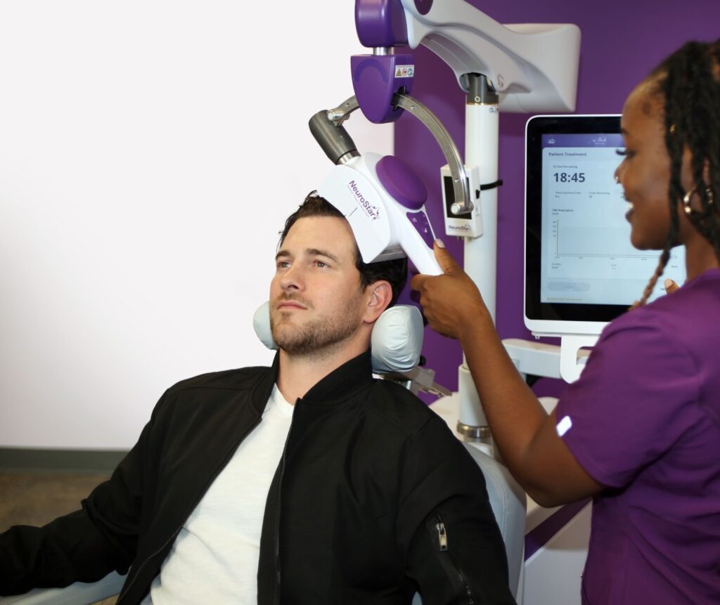 A male patient calmly receiving Transcranial Magnetic Stimulation therapy.