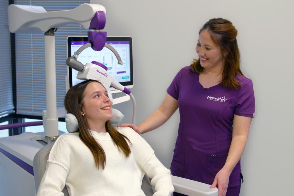 Patient seated in a treatment chair receiving noninvasive TMS therapy with a magnetic coil positioned near the forehead.